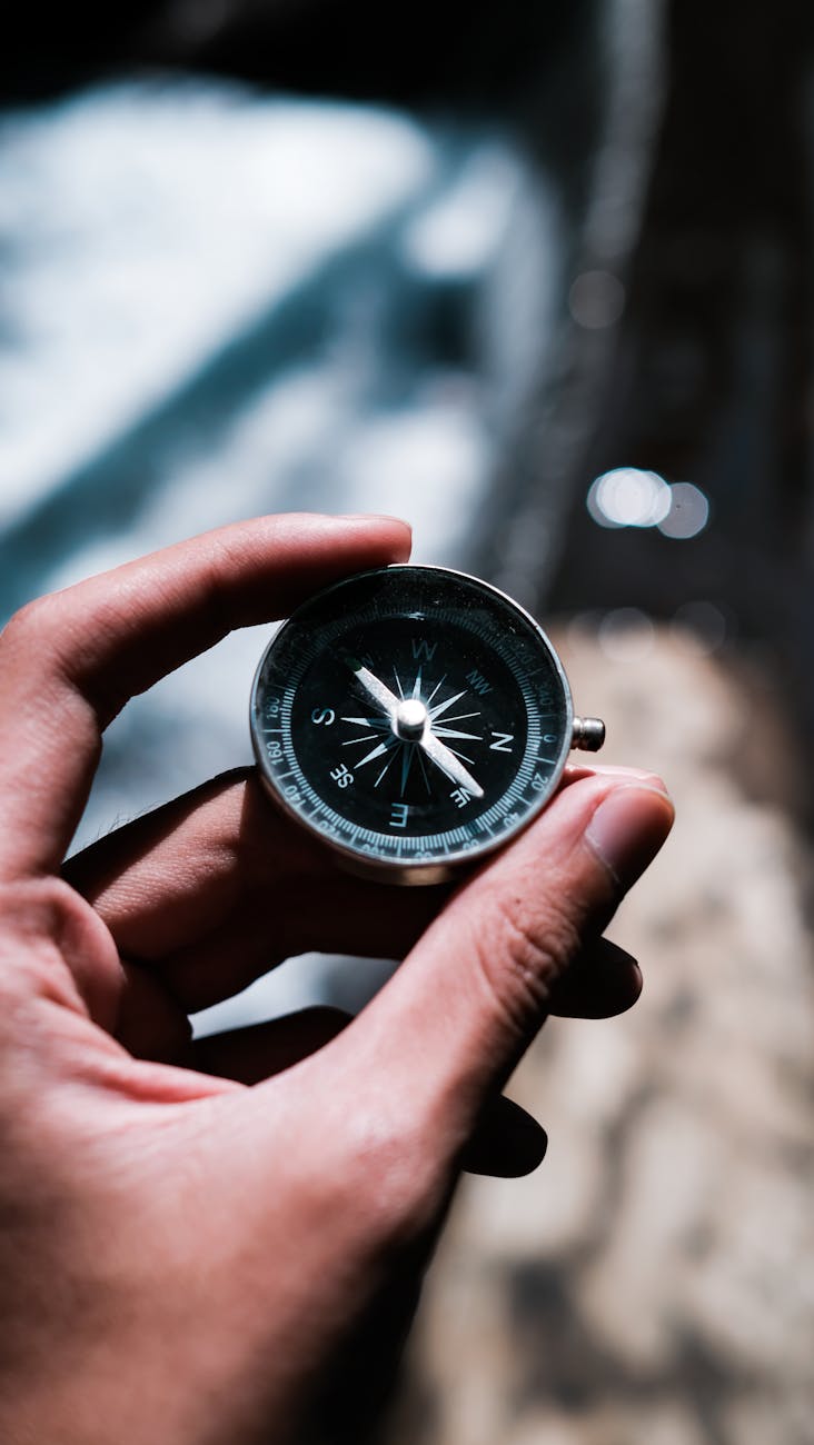 a person holding black and silver compass